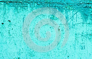Abstract background of an old time-damaged concrete wall covered with old green paint.