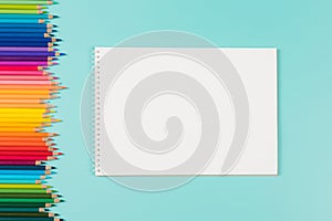 Abstract background for painting, drawing and sketching. Blank white paper spiral notebook and many colored pencils on