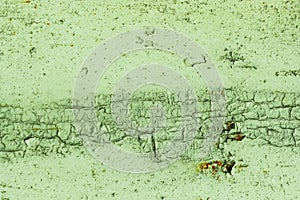 Abstract background of pastel green peeling and cracked paint on a concrete wall.