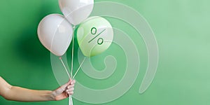 Abstract background with promotional ideas for product prices. Woman hand holding a white balloon in a green background