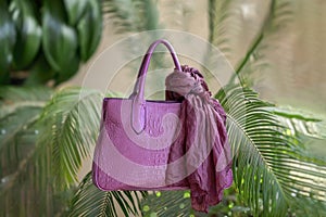 Abstract background of purple handbag embossed under exotic crocodile leather on a background of tropical green natural