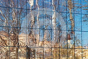 abstract background with reflection of trees and sky in the glass wall of the building