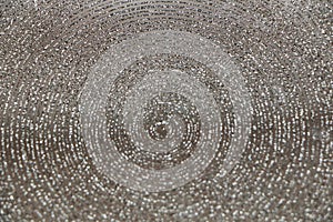 Abstract background of shiny rings of gray, black and beige colors with iridescent glitter