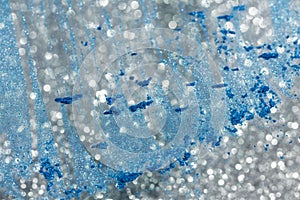 Abstract background with silver defocused glitter effect and blue powder on glass