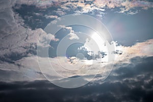 Abstract background, sun in blue sky and dark clouds.