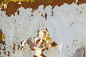 Abstract background texture of vertical grungy rusting metal plate with peeling paint and extensive corrosion with rust streaks.