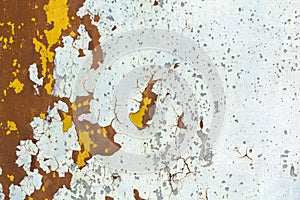 Abstract background texture of vertical grungy rusting metal plate with peeling paint and extensive corrosion with rust streaks.