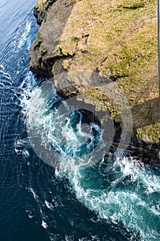 Abstract background. The waves of the sea water meet with underwater pointed rocks, forming whirlpools.