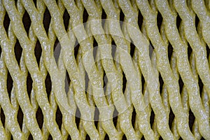 Abstract background of yellow plastic mesh texture for fruit, close up