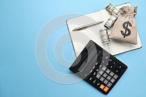 Abstract bag with money, calculator, pen and diary on a blue background with copy space