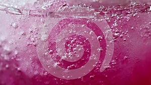 Abstract beauty in drink details. Extreme close-up of iced red soda in glass.