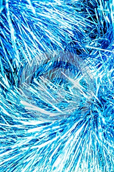 Abstract blue bokeh defocused background.New Year background photo with glowing blue tinsel. Close-up of shiny metallic