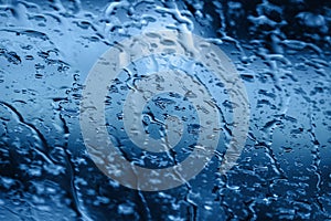 Abstract blue color background with water drops on glass surface with selective focus.