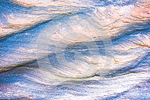 Abstract blue, gray, orange and green background - layers of rocks exposed by sea in Northumberland