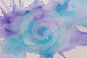 Abstract blue and purple watercolor paint on white canvas, top view