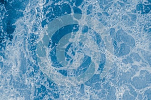 Abstract blue sea water with white foam and bubbles for background, natural summer background