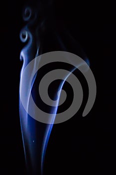 Abstract blue smoke swirls over black background