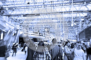 Abstract blue view of Waterloo Station with many passengers in a rush and a clock in London, England