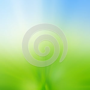 Abstract blur background of green grass field and blue sky above