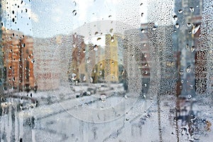 Abstract blurred background. Condensation drops on window. Winter cityscape outside window