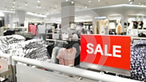 Abstract blurred background of red SALE signage on clothes shelf for clearance sales in woman zone at clothes shopping store