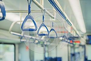 Abstract blurred background of subway train interior, blue handles for passengers, public transportation