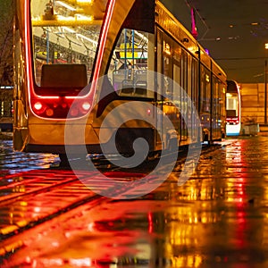 Abstract blurred background of tram on line at night, iluminated street, public transport stoping