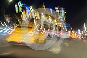 Abstract blurred image of yellow taxi, urban street night traffic with bokeh lights, night time, for background use