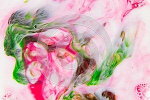 Abstract blurred pink-green texture of food dyes in milk.