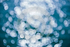 Abstract blurred shining sunlight bokeh on blue sea water background.