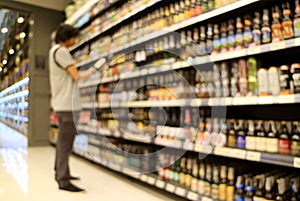 Abstract blurred shot of a man looking at the goods in front of grocery shelf in a retail store