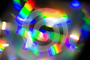 Abstract blurred unfocused background with bright raibow colored lights on a dark background