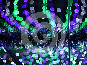 Abstract Bokeh light blurred background, lightbulb on Christmas tree for celebrate season with green, blue and purple colorful.