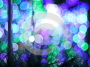 Abstract Bokeh light blurred background, lightbulb on Christmas tree for celebrate season with green, blue and purple colorful.