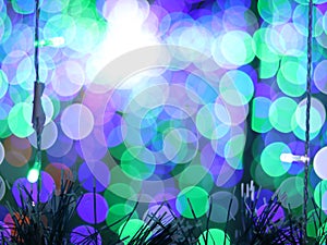 Abstract Bokeh light blurred background, lightbulb on Christmas tree for celebrate season with green, blue and purple colorful.