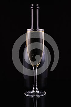 Abstract bottle champagne and glass with white sparkling wine on a black background.Festive concept