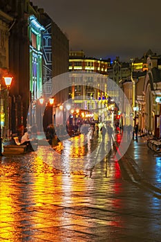 Abstract bright blurred background with people city street in rainy night. Vivid illumination, reflection, street lamps