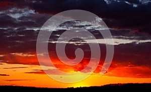 Abstract burning sky at sunset. Red clouds on the horizon are illuminated by evening sunlight