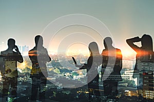 Abstract businesspeople silhouettes working together on dark city skyline wallpaper. Teamwork, colleagues and communication