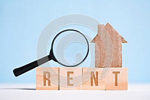 Abstract cardboard house, glass magnifier on cubes with the word rent. The concept of home search, the legality of the transaction