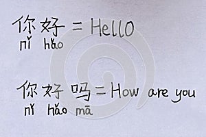 Closeup of paper handwritings homework in both Chinese with pinyin and English characters of Hello and How are you photo