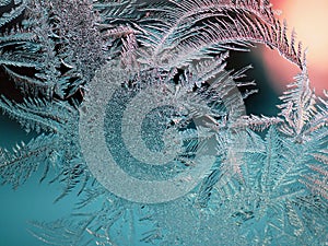 Abstract Christmas background. Ice crystals on frozen window glass. Frost drawing. Winter season theme. Dark turquoise and red