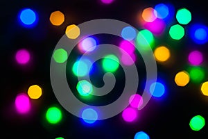 Abstract Christmas New Year garland multicolored neon ights close up blurred bokeh dark background