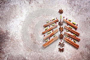 Abstract Christmas tree made of cinnamon sticks and spices. Beige grunge background. Top view, flat lay
