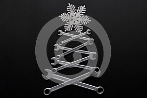 Abstract christmas tree made of wrenches with snowflake on the top on black background. Industrial christmas, winter, new year.