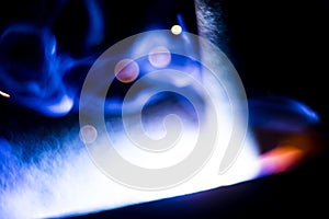 Abstract close-up image of blurred sparks and smoke from arc welding with bokeh effect