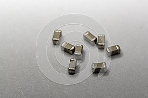 Abstract close-up of scattered 0603 SMT MLCC capacitors power electronics components white background in random pattern