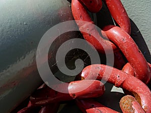 Abstract closeup of heavy welded steel red chain links in harbor