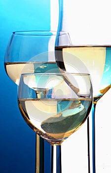 Abstract closeup, three wine glasses with white wine in front of