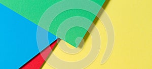 Abstract color papers geometry flat lay composition banner background with blue, yellow, red and green color tones